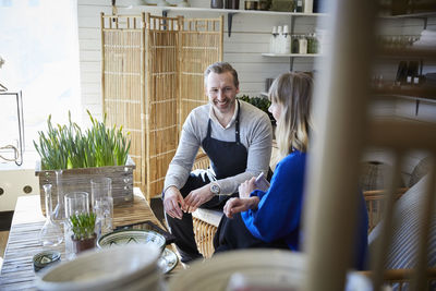 Smiling owner discussing with female colleague at store