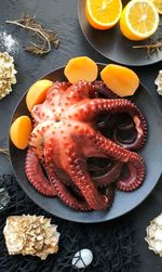 Freshly cooked octopus is lying on a black plate
