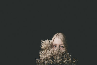 Portrait of woman with flowers against black background