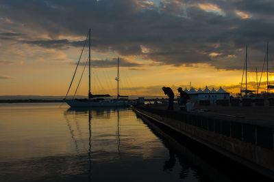 Sailboats moored in sea at sunset