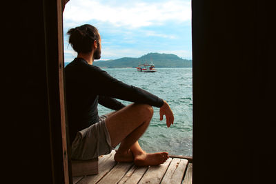 Side view of a man looking at the sea from a bungalow balcony