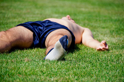 Shirtless soccer player sleeping on field