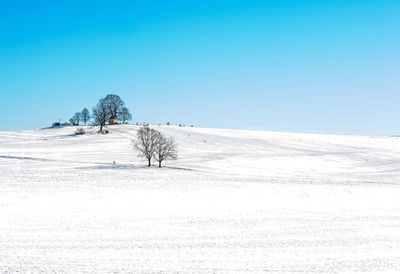 Scenic view of snow covered field against clear blue sky