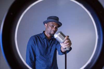 Portrait of man holding microphone standing in recording studio