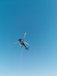 Low angle view of airplane flying against clear blue sky