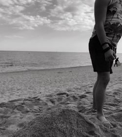 Low section of woman on beach against sky