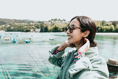 Portrait of smiling young woman sitting against lake