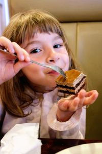 Portrait of cute girl eating cake slice at restaurant