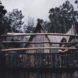 Boy by trees against sky