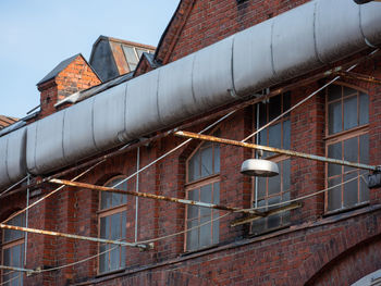 A close-up of the wall of a lamp hanging on an old red brick industrial factory building.