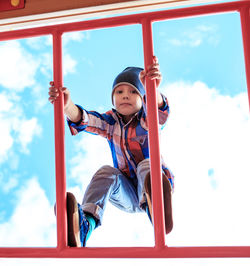 Full length of boy sitting against sky