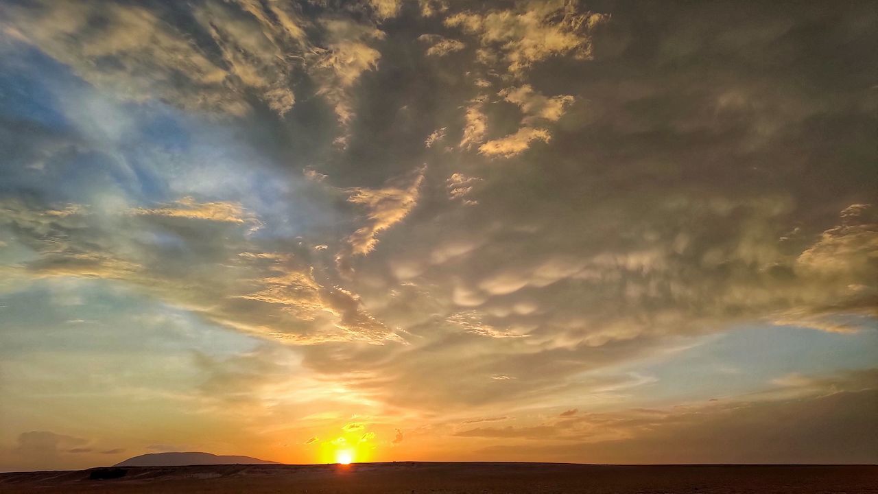 SUN STREAMING THROUGH CLOUDS DURING SUNSET