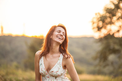 Smiling mature woman standing against sky during sunset
