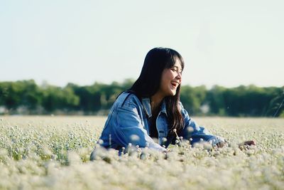 Smiling girl sitting by blooming flowers