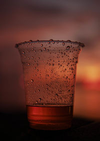 Close-up of drink in glass with sunset background