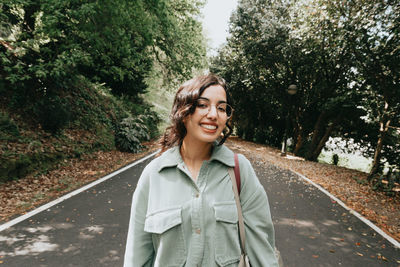 Portrait of young woman standing against trees