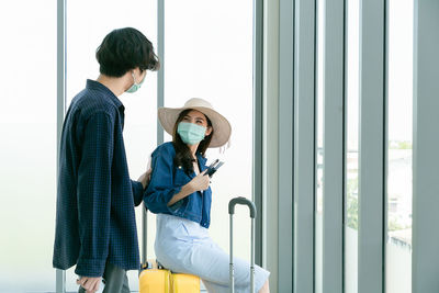 Side view of young woman looking through window