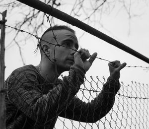 Young man looking through fence