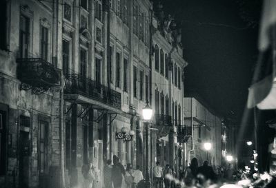 Illuminated street amidst buildings in city at night