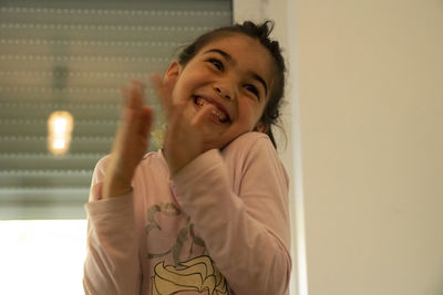 Smiling girl clapping at home