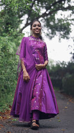 Portrait of young woman standing against trees