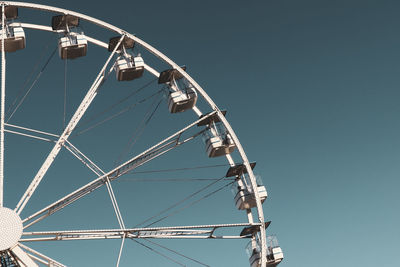 Low angle view of ferris wheel against clear blue sky