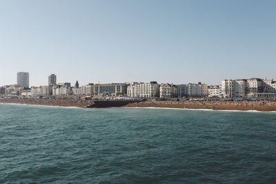 Scenic view of sea by buildings against clear sky on sunny day