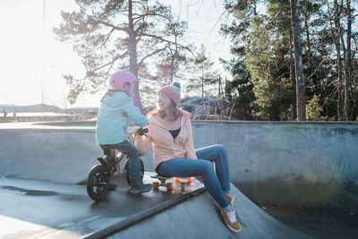 Woman playing with her daughter in a skatepark outside in the sunshine