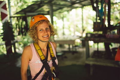Portrait of smiling woman wearing safety harness with headwear outdoors