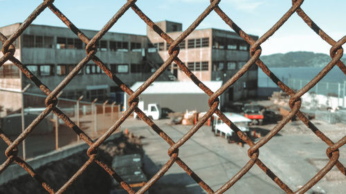 Close-up of chainlink fence against building in city