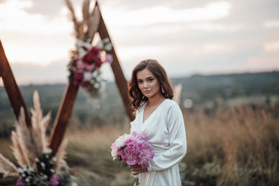 Portrait of a smiling young woman standing against plants