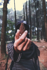 Midsection of person holding leaf in forest