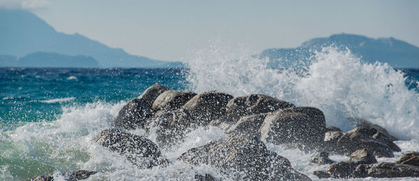 Panoramic view of sea waves splashing on rocks