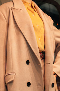 Details of a seasonal beige coat and a bright yellow shirt. casual women's fashion