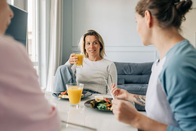 A group of female friends sitting at the table having breakfast and chatting.