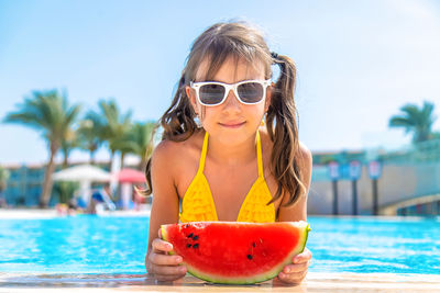 Smiling girl with watermelon by swimming pool
