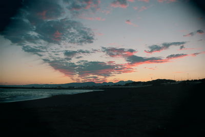 Scenic view of beach against sky at sunset