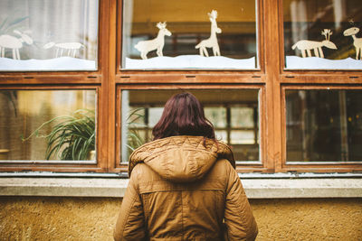 Rear view of woman standing against window