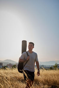 Young man standing on field against clear sky