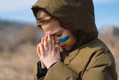 Cute boy praying against sky