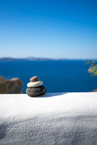 Close-up shot of pebbles stacked on each other in a balance with santorini caldera in the background