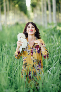 Portrait of smiling young woman standing amidst grass