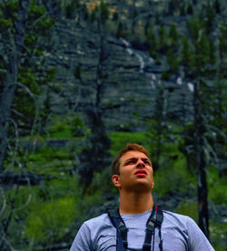 Young man looking up in forest