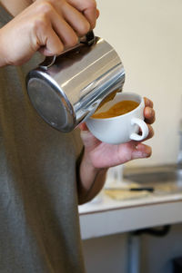 Barista having latte art coffee in white mug.