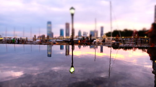 Sailboats in city against sky at sunset