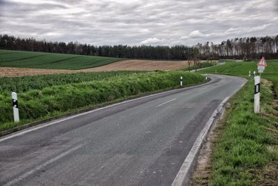 Empty road amidst crops growing on farm