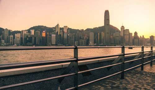 Buildings by river against sky during sunset