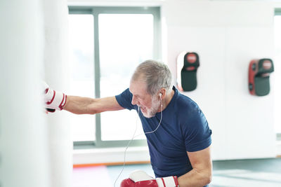 Fit senior man in boxing gloves fighting