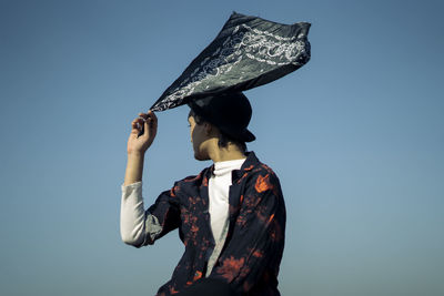 Woman holding umbrella against clear sky