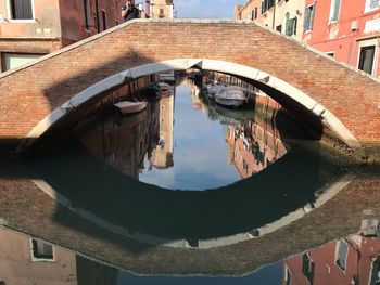 Arch bridge over canal amidst buildings in city